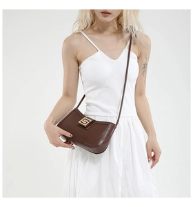 Detail of vintage brown leather shoulder bag featuring a rectangular gold metal clasp