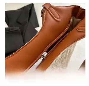 Detail of smooth zipper closure and premium brown leather trim on woven straw tote bag