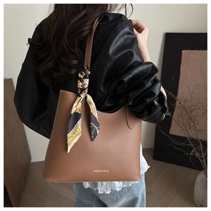 Brown tote bag with decorative silk scarf shown on shoulder for sizing and fit