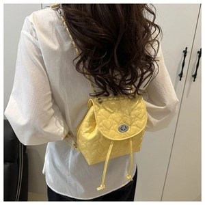 Close-up of yellow mini backpack featuring heart quilted pattern and silver twist lock