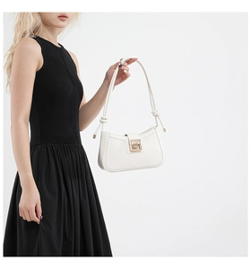 Detail of white leather shoulder bag with gold metal buckle on black dress background