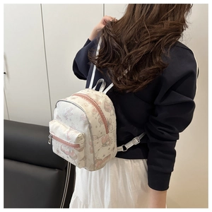 Rear view of a mini cream backpack with butterfly prints on a model with silver straps