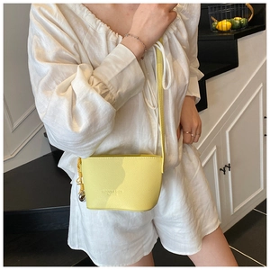 Detail of bright yellow bucket bag with lychee texture and thin crossbody shoulder strap