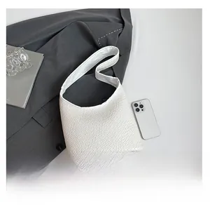 Detail shot of white crocodile embossed hobo bag shown with a smartphone for scale
