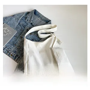 Detail of white corduroy shoulder tote bag with a matching small coin purse and leather patch