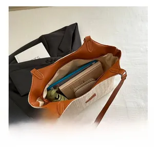 Detail view of large straw tote bag showing spacious interior with laptop and wallet