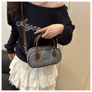Detail of blue denim mini bag with brown leather trim and golden hardware buckle