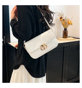 Detail of a cream faux leather crossbody bag with a gold horseshoe buckle on a model