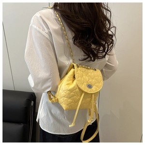 Detail of yellow quilted heart backpack with chain strap on model's back for daily use