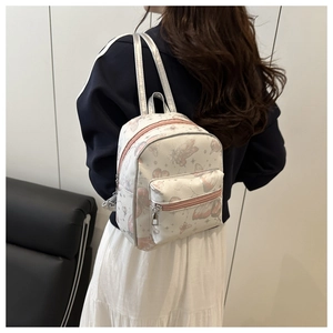Rear view of a model wearing a mini white backpack with pink butterfly and star prints