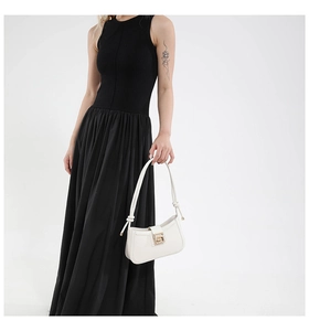 Close-up of white leather shoulder bag with knotted handle detail and gold buckle on a model