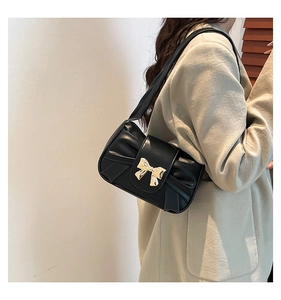 Detail of black leather pleated underarm bag with decorative gold bow buckle