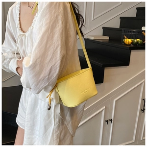 Detail of yellow lychee texture crossbody bucket bag with decorative rope knot and metal clasp