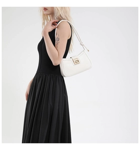 Close-up of white leather shoulder bag featuring golden clasp and dual knotted strap detail