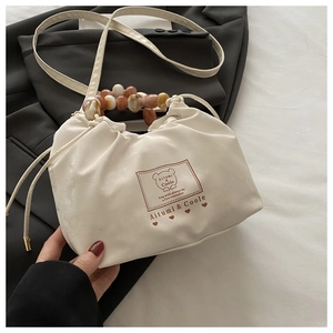 Detail of cream white beaded handbag with marble texture handle and brand lettering