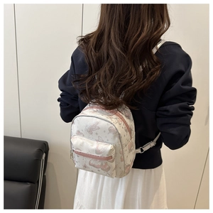 Rear view of model wearing a white mini backpack with pink butterfly prints and pink zippers