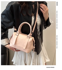 Détail du sac à main rose clair en cuir avec lettrage gaufré et finitions argentées