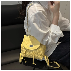 Detail of yellow mini backpack with heart quilting, silver swivel lock, and chain straps