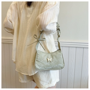 Detail of light green pleated shoulder bag with silver butterfly and ribbon knot strap