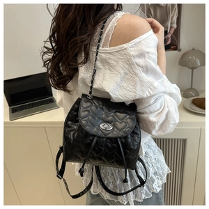 Detail of a black mini quilted backpack featuring heart patterns and silver twist lock