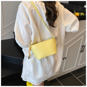 Detail of yellow lychee texture bucket bag featuring metal ball charm and logo embossing