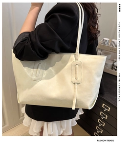 Detailed view of cream soft faux leather tote bag with elegant stitching on model