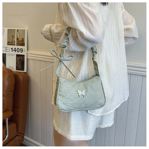 Detail of light green pleated underarm bag featuring a silver butterfly buckle and bow strap