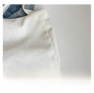 Detailed close-up of white corduroy fabric texture with vertical striped patterns