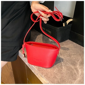 Detailed close-up of red lychee textured bucket bag featuring fashion text and metallic zipper