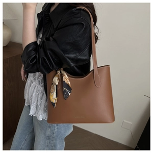 Detailed view of brown leather tote bag accented with stylish geometric pattern silk scarf