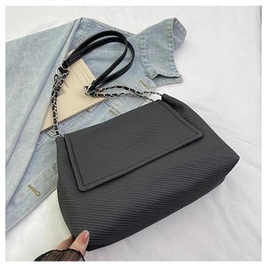 Detail of black woven tote bag with silver chain strap and minimalist quilted texture