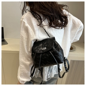 Detail of heart quilted stitching and silver twist lock on mini black leather backpack