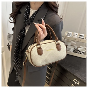 Detail of retro bowling bag with cream fabric, brown leather trim and gold hardware