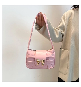 Detail of pink French-style baguette bag featuring a large bow and golden butterfly clasp