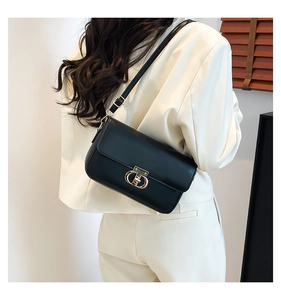 Detail of a minimalist black PU leather crossbody bag with a gold double-ring clasp