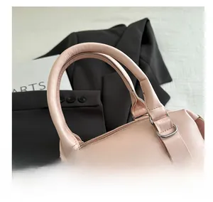 Détail du sac Boston rose montrant les poignées rondes et le lettrage en similicuir