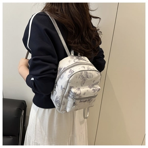 Detail of white mini backpack featuring gray butterfly prints and silver metal zippers