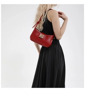 Detail of red leather shoulder bag featuring a gold square twist lock and knotted strap