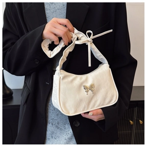 Detail of silver butterfly buckle and pleated handle on cream white shoulder bag