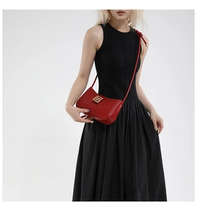 Close-up of red leather handbag featuring gold interlocking buckle and knot detail