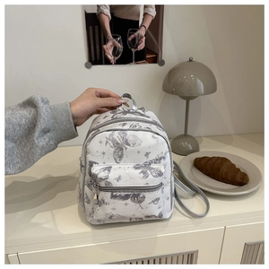 Detailed shot of white mini backpack featuring silver butterfly and celestial patterns
