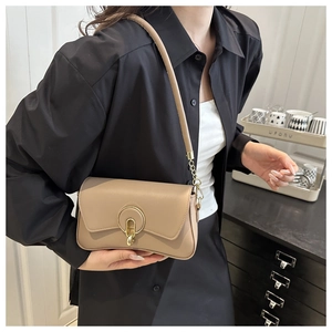 Detail of light tan faux leather square bag with golden semi-circular metal lock and chain