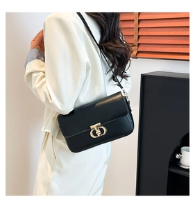 Detail of a black PU leather crossbody bag with a gold metal clasp worn by a model