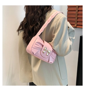 Detailed view of pink pleated shoulder bag with a decorative gold metal bow buckle