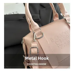 Détail du crochet en métal argenté et du logo gaufré sur le sac à main rose