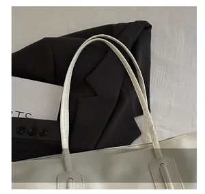 Close-up of white tote bag handle with reinforced stitching and hollow decorative detail