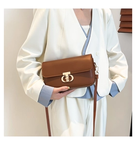 Detail of trendy brown PU leather bag with unique gold metallic swivel lock closure