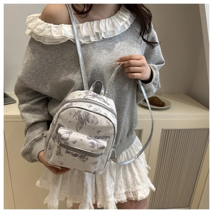 Detail of mini backpack with grey butterfly floral pattern and silver metal zippers