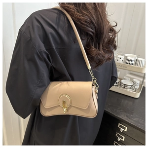 Detail view of beige crossbody square bag with gold circular buckle on a wide shoulder strap