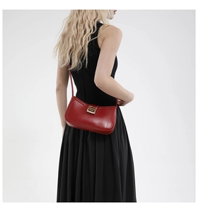 Close-up of bright red vintage saddle bag with gold geometric clasp on black dress